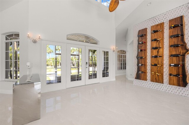 unfurnished living room featuring high vaulted ceiling, french doors, and tile floors