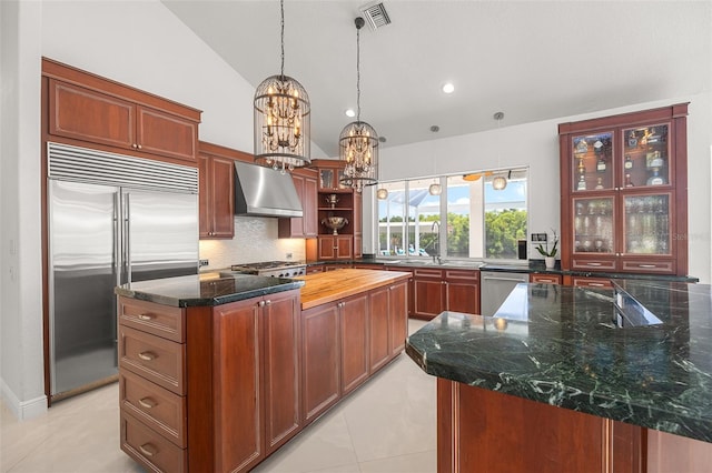 kitchen featuring appliances with stainless steel finishes, a center island, wall chimney exhaust hood, and light tile floors