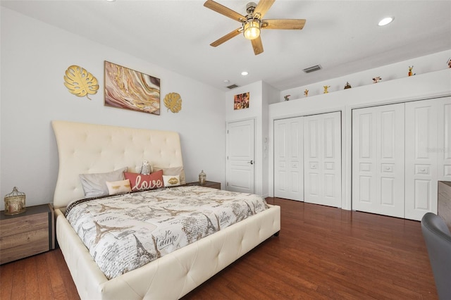 bedroom with multiple closets, ceiling fan, and dark hardwood / wood-style floors