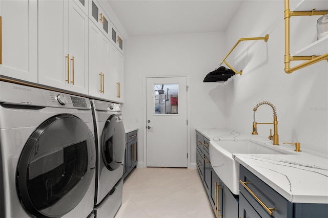 laundry room featuring washer and dryer, cabinets, sink, and light tile flooring