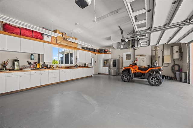 garage with a workshop area, a garage door opener, and stainless steel refrigerator