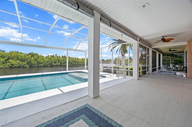 view of pool with glass enclosure, a water view, a patio area, and ceiling fan