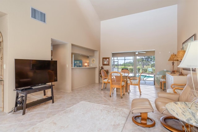 tiled living room featuring ceiling fan and a towering ceiling