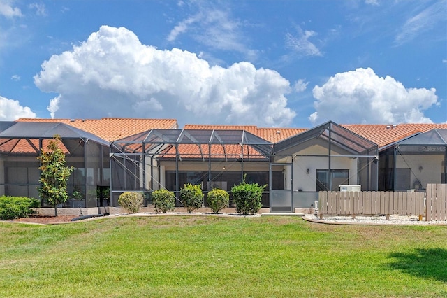 rear view of property with a lawn and glass enclosure