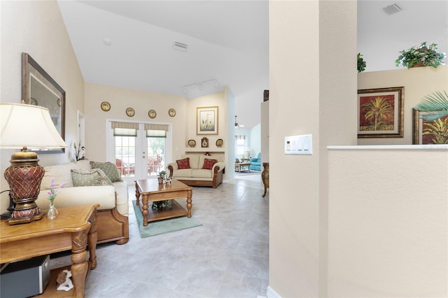 living room featuring lofted ceiling, track lighting, and french doors