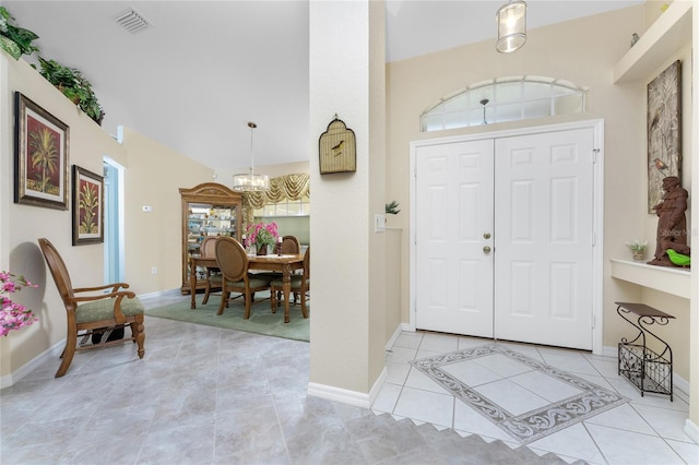 entrance foyer featuring an inviting chandelier, light tile patterned floors, and vaulted ceiling