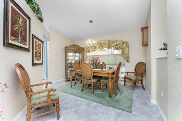 dining room featuring vaulted ceiling, light tile patterned floors, and a notable chandelier