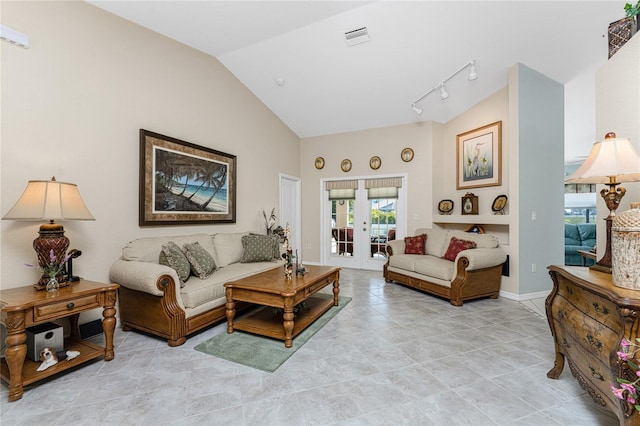 tiled living room with rail lighting, high vaulted ceiling, and french doors