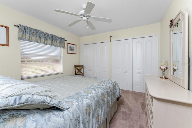 carpeted bedroom featuring multiple closets and ceiling fan