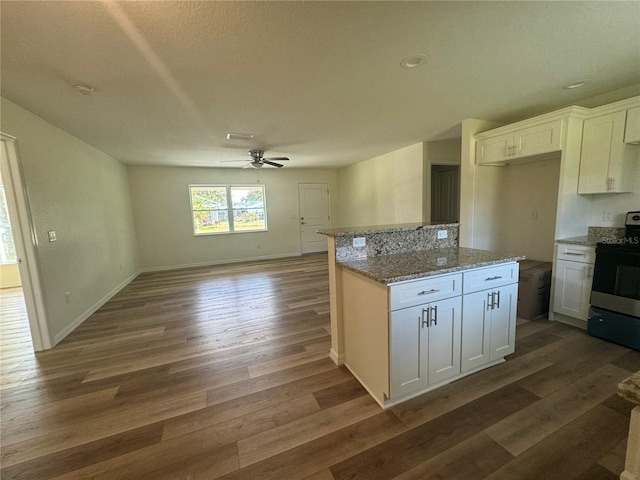 kitchen with dark wood-type flooring, range with electric stovetop, and white cabinets