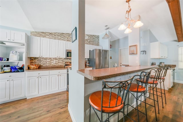 kitchen with a kitchen bar, appliances with stainless steel finishes, light hardwood / wood-style flooring, and white cabinetry