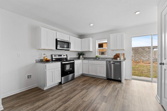 kitchen with dark hardwood / wood-style floors, sink, white cabinetry, stainless steel appliances, and light stone countertops