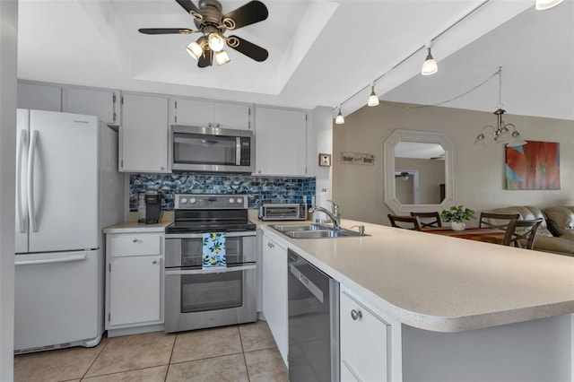 kitchen with kitchen peninsula, appliances with stainless steel finishes, tasteful backsplash, a raised ceiling, and ceiling fan