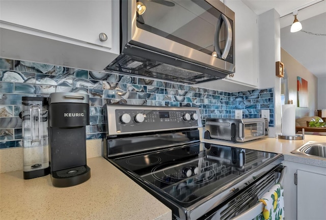 kitchen with backsplash, white cabinetry, and stainless steel appliances