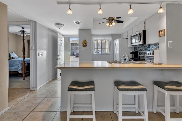 kitchen featuring a breakfast bar area, kitchen peninsula, white cabinetry, and stainless steel appliances