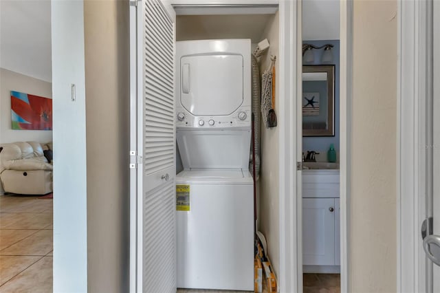 laundry area featuring stacked washing maching and dryer, sink, and light tile patterned floors