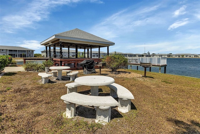 view of dock with a gazebo, a yard, and a water view