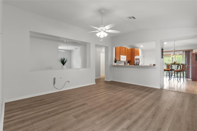 unfurnished living room featuring vaulted ceiling, ceiling fan, and light wood-type flooring