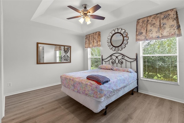 bedroom featuring a raised ceiling, hardwood / wood-style floors, and ceiling fan