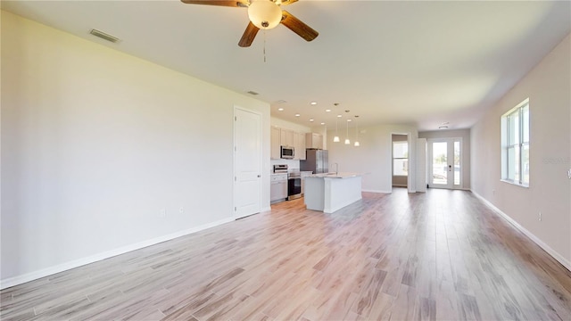 unfurnished living room with ceiling fan, light hardwood / wood-style floors, sink, and french doors