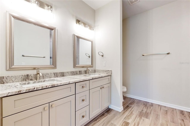 bathroom with wood-type flooring, vanity, and toilet