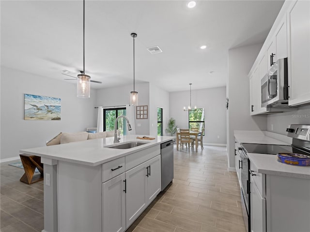 kitchen with sink, hanging light fixtures, a center island with sink, white cabinets, and appliances with stainless steel finishes