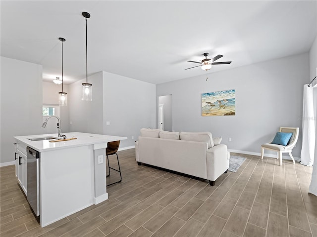 kitchen with a kitchen island with sink, sink, light hardwood / wood-style flooring, ceiling fan, and decorative light fixtures