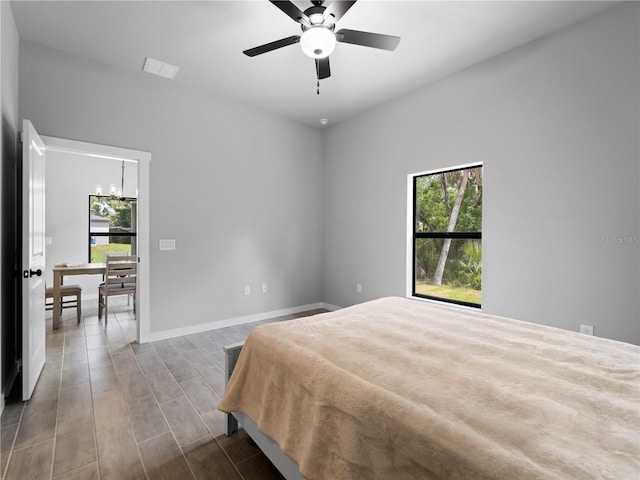 bedroom featuring hardwood / wood-style floors and ceiling fan with notable chandelier