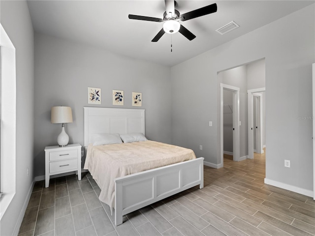 bedroom with ceiling fan, a walk in closet, and light hardwood / wood-style flooring