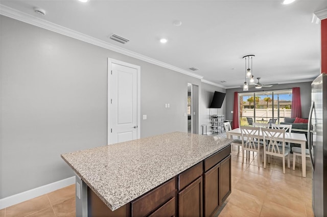 kitchen featuring crown molding, ceiling fan, stainless steel fridge, light tile patterned floors, and a kitchen island