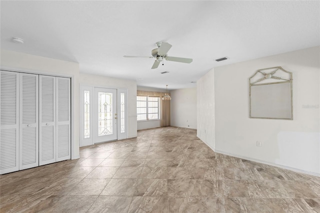 empty room featuring ceiling fan with notable chandelier