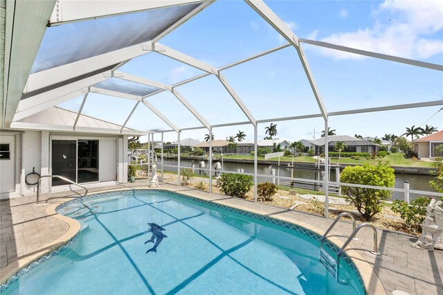 view of pool featuring glass enclosure, a patio area, and a water view