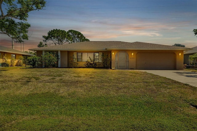 ranch-style home featuring a garage and a lawn