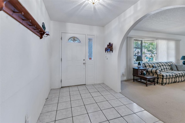 entryway with light carpet and a textured ceiling