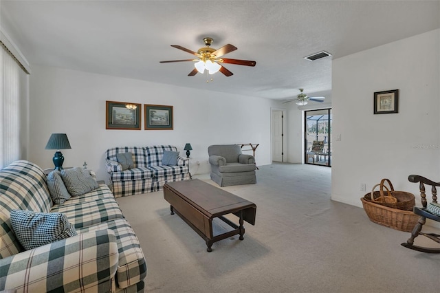 carpeted living room featuring ceiling fan and a textured ceiling