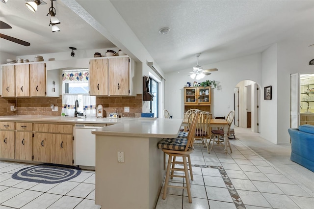 kitchen with tasteful backsplash, light tile patterned floors, white dishwasher, and vaulted ceiling