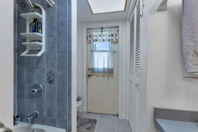 bathroom with toilet, tile patterned flooring, and tiled shower / bath