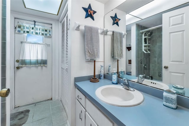 bathroom with tile patterned flooring, a tile shower, and vanity