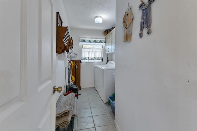 laundry room featuring washing machine and clothes dryer, light tile patterned flooring, cabinets, and a textured ceiling