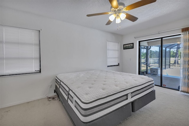 carpeted bedroom with access to exterior, ceiling fan, and a textured ceiling