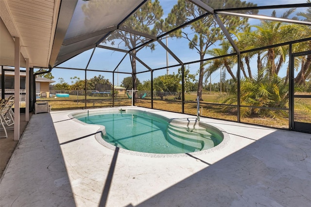 view of swimming pool featuring glass enclosure, a yard, and a patio