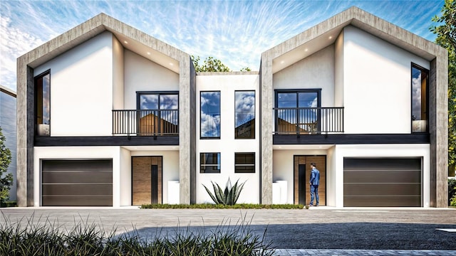 contemporary home featuring stucco siding, a garage, a balcony, and driveway