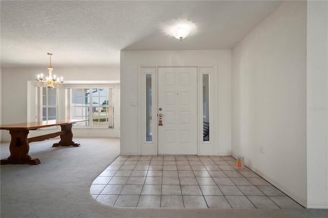 foyer entrance with a notable chandelier, light colored carpet, and a textured ceiling