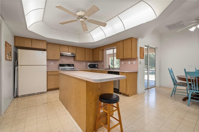 kitchen featuring backsplash, ceiling fan, a center island, and white appliances