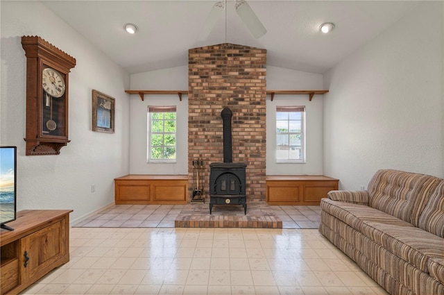 living room with a healthy amount of sunlight, a wood stove, ceiling fan, and lofted ceiling