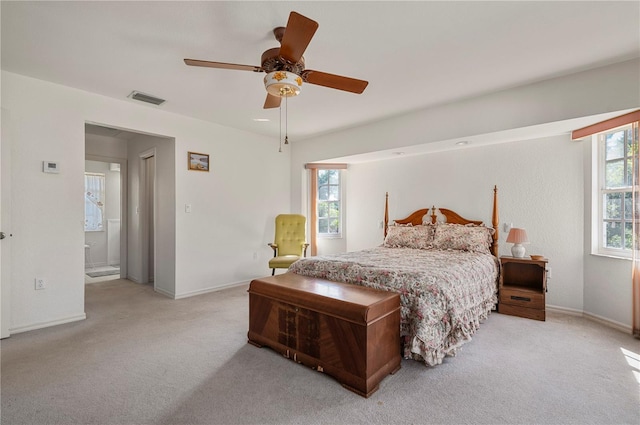 carpeted bedroom featuring multiple windows, ensuite bath, and ceiling fan