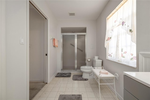 bathroom with tile patterned floors, vanity, toilet, and a shower with door