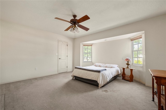 carpeted bedroom with ceiling fan, a textured ceiling, and multiple windows