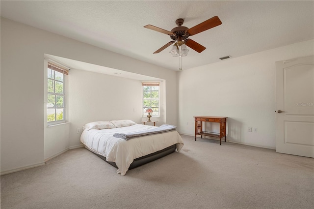 carpeted bedroom with ceiling fan and a textured ceiling