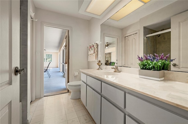 bathroom with walk in shower, ceiling fan, vanity, and toilet